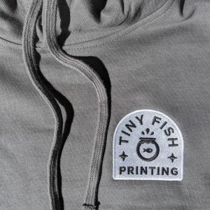 Fill-stitch embroidery with the Tiny Fish Printing logo.